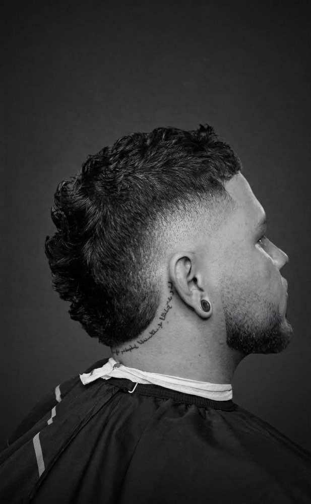 Mullet rizado con burst fade alrededor de la oreja